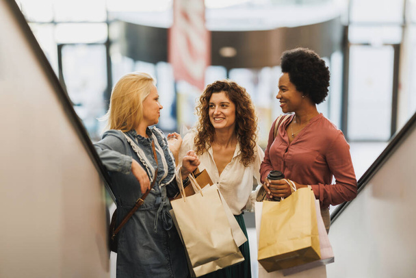 Shot van drie aantrekkelijke gelukkige vrouwen nemen wat tijd uit om te genieten van een shopping spree in de stad winkelcentrum. - Foto, afbeelding