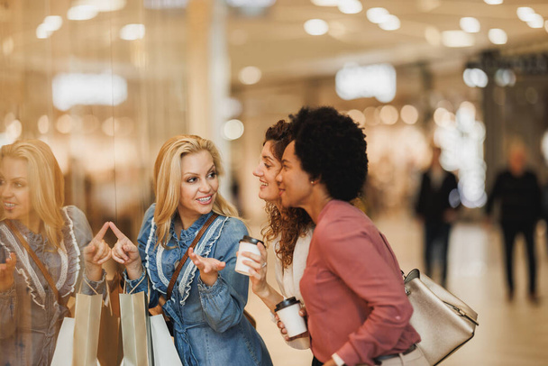 Kara Cuma ya da Siber Pazartesi satışları sırasında alışveriş merkezinde eğlenmek için ara veren üç gülümseyen kadın.. - Fotoğraf, Görsel
