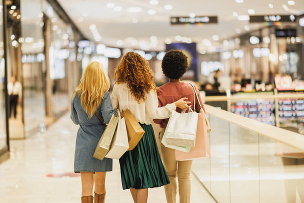 Üç kadın en iyi arkadaşın alışveriş merkezinde eğlenirken, eğlenirken ve kucaklaşırken arka planda görüntüsü.. - Fotoğraf, Görsel