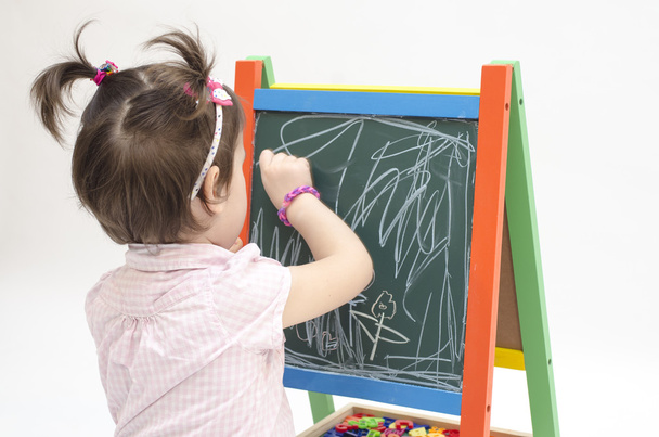 Little girl scratches with chalk on blackboard - Φωτογραφία, εικόνα