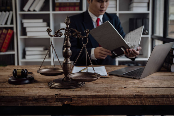Aziatisch man advocaat werken in kantoor met laptop en schalen, rechter hamer, juridisch adviseur concept. - Foto, afbeelding