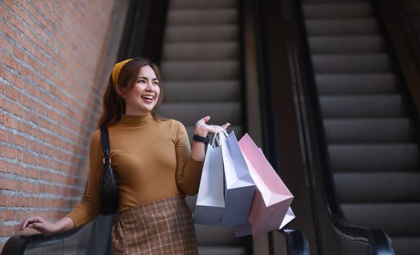 Alışveriş merkezindeki güzel Asyalı kadın alışveriş torbalarıyla mutlu kadın alışverişi yapıyor.. - Fotoğraf, Görsel