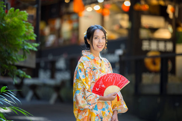 Femme asiatique essayer de porter kimono japonais avec l'arrière-plan traditionnel du village japonais - Photo, image