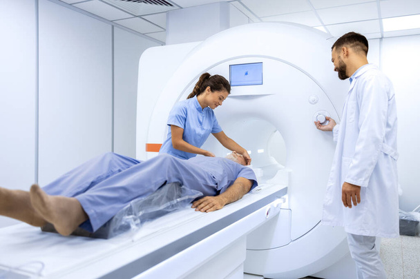 Kobieta lekarz asystujący starszemu pacjentowi podczas tomografii magnetycznej w sali badań lekarskich. - Zdjęcie, obraz