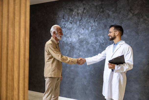 Médico e paciente apertando as mãos no lobby do hospital moderno. - Foto, Imagem