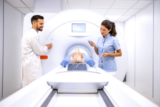 Radyolog ve bayan teknisyen hastayı hastane teşhis odasında MRI prosedürüne hazırlıyorlar.. - Fotoğraf, Görsel