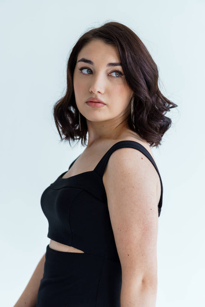 Portrait of a young beautiful girl in a black dress on a gray background - Foto, Imagem