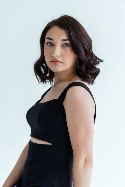 Portrait of a young beautiful girl in a black dress on a gray background - Foto, immagini