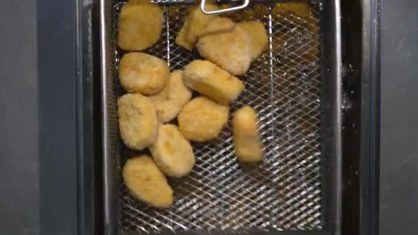Cocine nuggets tempura de pollo en la freidora. Coloca los trozos de pollo en el aceite caliente. Primer plano - Metraje, vídeo