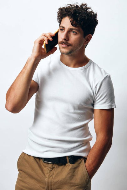 mężczyzna mobilny portret pewnie patrząc połączenie męski szczęśliwy mężczyzna styl życia Boże Narodzenie t-shirt biały telefon tło hipster kaukaski wiadomość telefon czat sms technologia zakupy - Zdjęcie, obraz