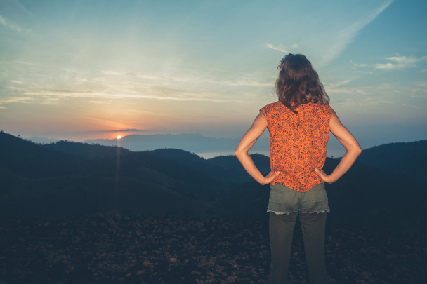 Femme regardant le lever du soleil sur les montagnes
 - Photo, image