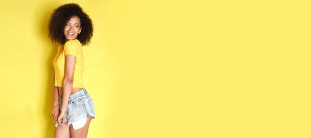 Cute female with curly hair on yellow background. - Photo, Image