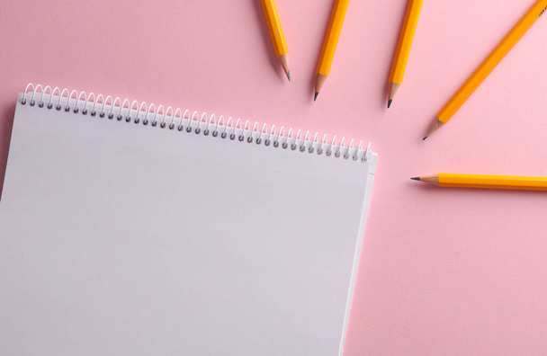 Білий порожній ескіз для малювання з набором олівців на рожевому фоні. Вид зверху - Фото, зображення