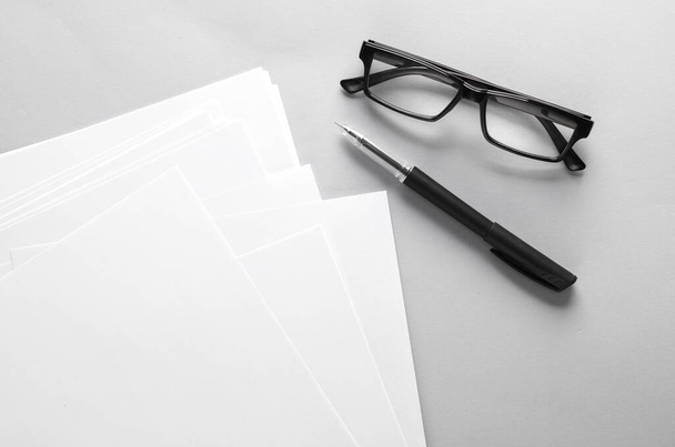 Fogli bianchi vuoti di formato carta a4 o modelli di documenti con penna e occhiali su sfondo grigio. Modello per il design - Foto, immagini