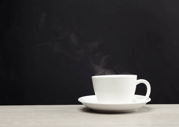 Biały ceramiczny kubek z gorącą kawą, para na czarnym tle - Zdjęcie, obraz