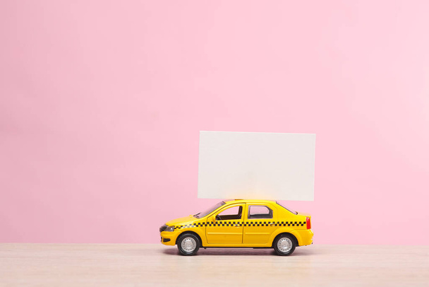 Miniaturní taxi auto s bílou vizitkou na růžovém pozadí - Fotografie, Obrázek