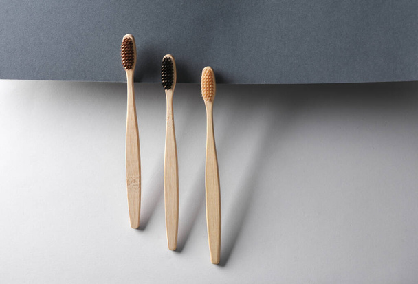 Wooden eco toothbrushes on black and gray background. Creative layout. Minimalism composition. - Photo, Image