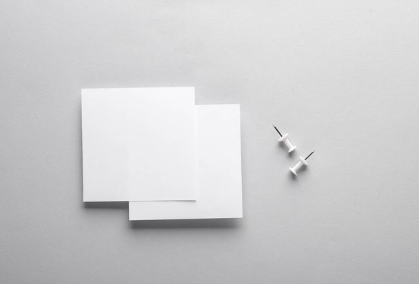 Białe puste kwadratowe arkusze notatek papieru z popychaczami na szarym tle. Wzór wzoru. - Zdjęcie, obraz