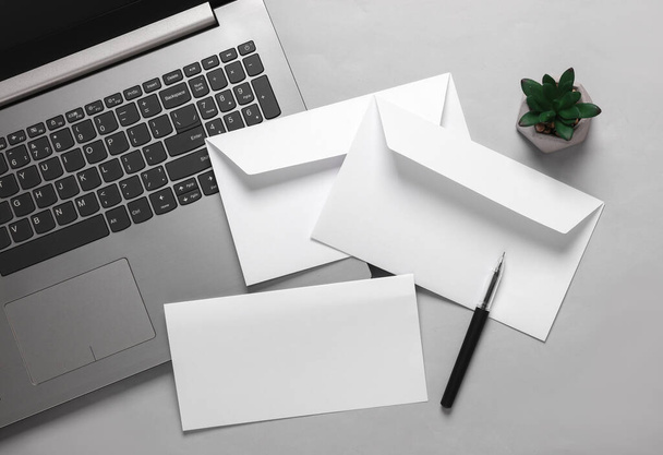 Diseño creativo de negocios desde un sobre blanco con una carta y un portátil sobre un fondo gris. Plantilla para diseño - Foto, Imagen