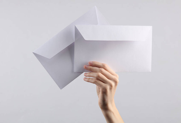 женская рука держит два белых конверта на сером фоне - Фото, изображение