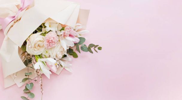 Beautiful bouquet with roses, carnations, iris and eucalyptus on a pink background, copy space. Mothers day, 8 march, holiday gift concept - Photo, Image