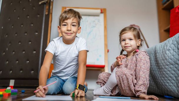 one small caucasian boy with sister child draw with crayon at home - Photo, Image
