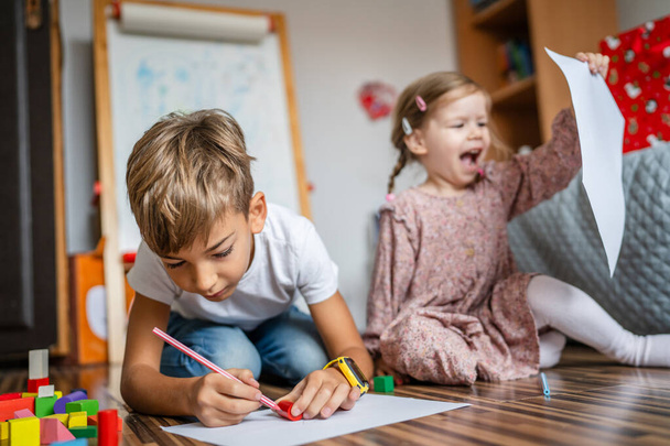 ein kleiner kaukasischer Junge mit Schwesterkind zeichnet zu Hause mit Buntstift - Foto, Bild