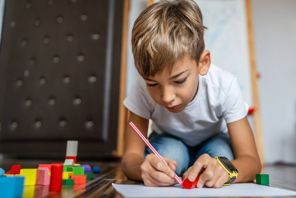 yksi pieni valkoihoinen poika koulupoika lapsi piirtää värikynällä kotona - Valokuva, kuva