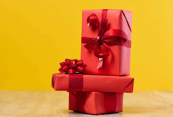 Pudełko zapakowane w czerwony prezent i czerwoną wstążkę na żółtym tle - Zdjęcie, obraz
