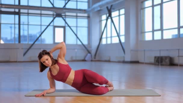 chica muscular en ropa deportiva roja haciendo el popular Kneeling Side Kicks ejercicio  - Imágenes, Vídeo