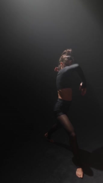 Egy titokzatos fiatal hölgy táncol egy kortárs darabot félhomályban. Kiváló minőségű 4k felvételek - Felvétel, videó