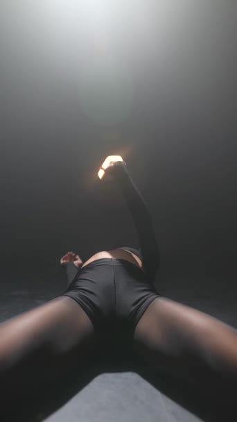 Realizando em um estúdio mal iluminado, uma linda garota de roupas pretas está dançando uma rotina moderna. Imagens 4k de alta qualidade - Filmagem, Vídeo