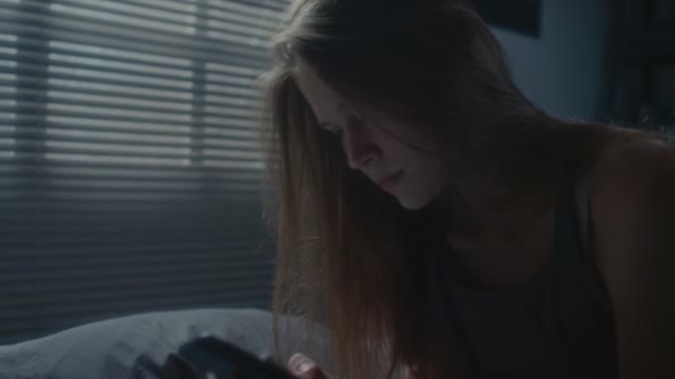 Tilt up πλάνο του νευρικού κοριτσιού κάθεται στο σκοτεινό υπνοδωμάτιο, doomscrolling στο τηλέφωνο και αίσθημα άγχους κατά τη διάρκεια της νύχτας - Πλάνα, βίντεο