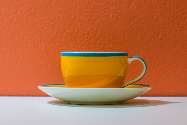 オレンジ色の壁,タイの黄色いコーヒー カップ. - 写真・画像