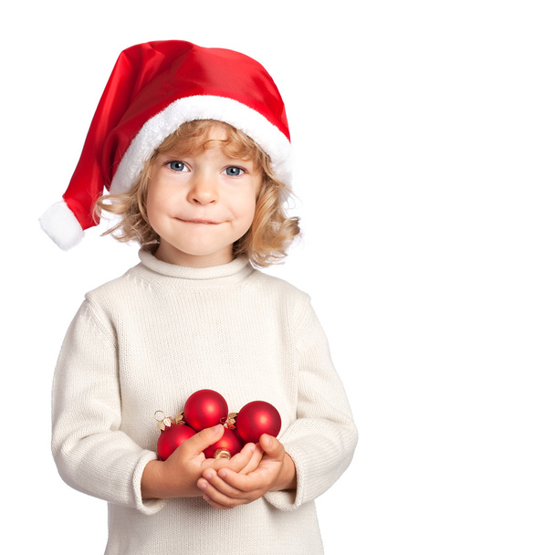 Smiling child in Santa hat with Christmas balls on white backgro - Fotoğraf, Görsel