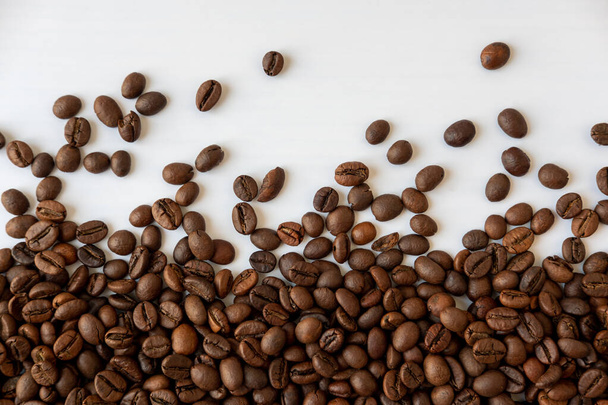 Koffiebonen verspreid over een witte achtergrond - Foto, afbeelding
