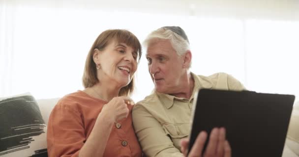 Tablet-, golf- en videogesprek met een senior koppel op een bank in de woonkamer van hun appartement samen. Technologie, glimlach of virtuele communicatie met een gelukkig oudere man en vrouw die online praten. - Video