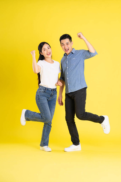 Ganzkörperbild des asiatischen Paares posiert auf gelbem Hintergrund - Foto, Bild