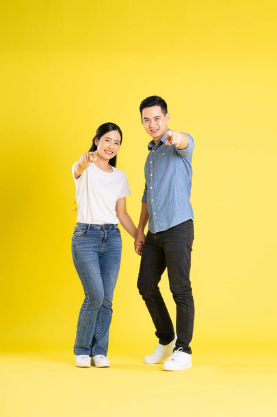 Ganzkörperbild des asiatischen Paares posiert auf gelbem Hintergrund - Foto, Bild