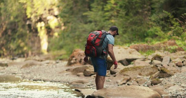 El turista activo camina a lo largo de un desfiladero rocoso con un río de montaña. Recreación activa en las montañas. - Foto, imagen