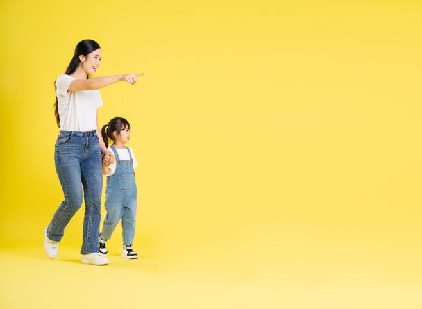 Bild von asiatischen Mutter und Tochter posiert auf einem gelben Hintergrund - Foto, Bild