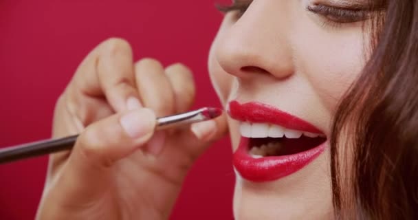 Beauty, makeup and red lipstick with brush and woman in studio background for cosmetics, smile and glamour. Glow, self care and skincare with face of female model for foundation and elegant style. - Footage, Video