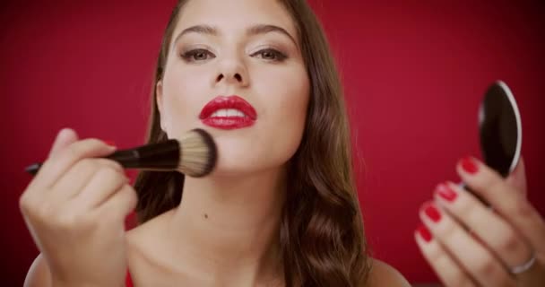 Woman, face and foundation brush in studio with application, beauty and skin by red background. Girl, model and cosmetic change with product for facial transformation, skincare or makeup for wellness. - Footage, Video