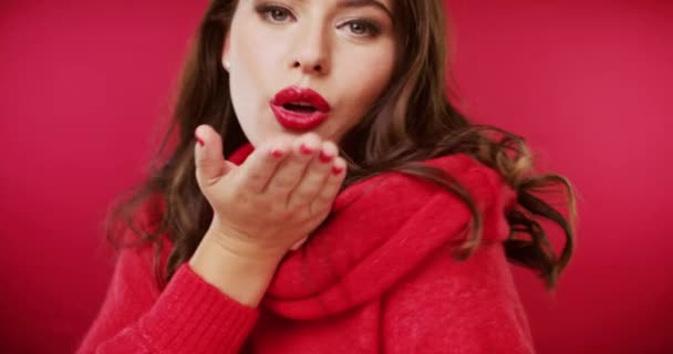 Woman, face and hand for kiss in studio on red background for valentines day beauty, cosmetics as mockup space. Female person, model and flirt smile for confidence, blowing gesture as emoji laugh. - Footage, Video