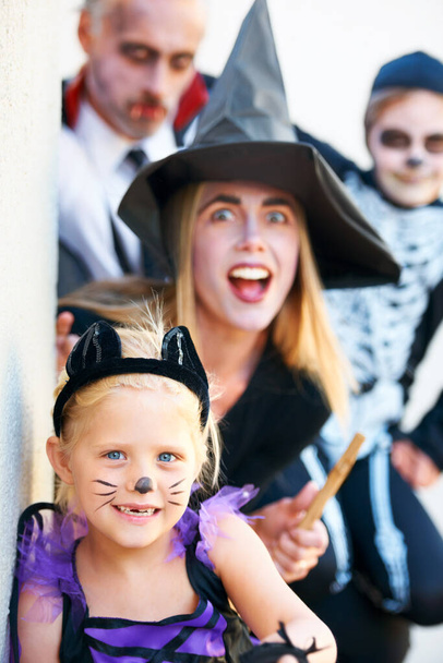 Portrait, halloween and a family in costume for fantasy tradition or holiday celebration. Mother, father and children at a door in trick or treat clothes for dress up on allhallows eve together. - Photo, Image