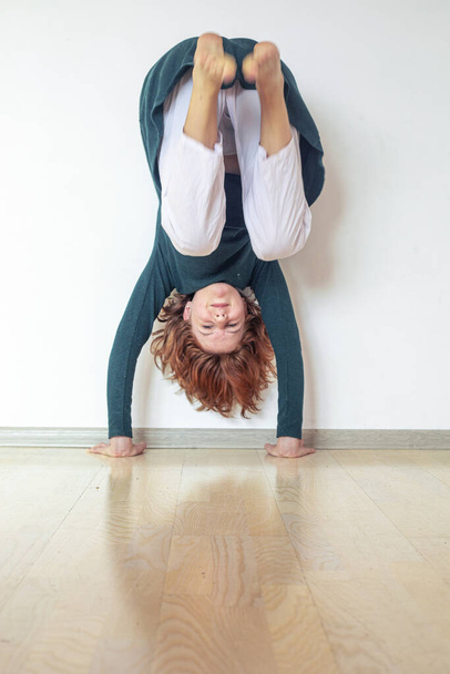  adolescente practicando haciendo un handstand cerca de la pared en su habitación - Foto, Imagen
