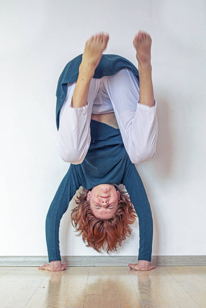  adolescente practicando haciendo un handstand cerca de la pared en su habitación - Foto, Imagen