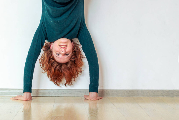girl practicing doing a handstand near the wall in her room - Photo, Image