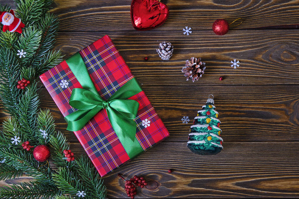 Weihnachtskomposition. Weihnachtsbaumzweige und rote Geschenkschachtel auf dem alten Holztisch aus nächster Nähe - Foto, Bild