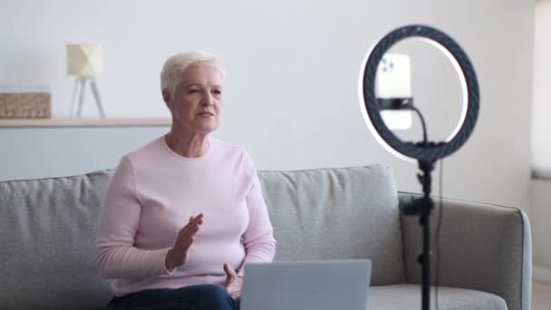 Mulher idosa equilibrada se envolve ativamente em uma videoconferência profissional, olhos focados na tela com determinação e experiência. Rodeado pelos confortos familiares do escritório em casa. - Filmagem, Vídeo